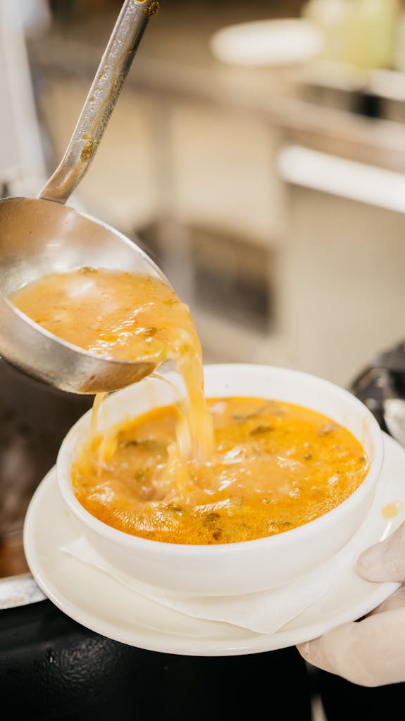 A ladle serving hot Turkish soup into a white bowl, showcasing traditional cuisine in Ünye, Turkey.
