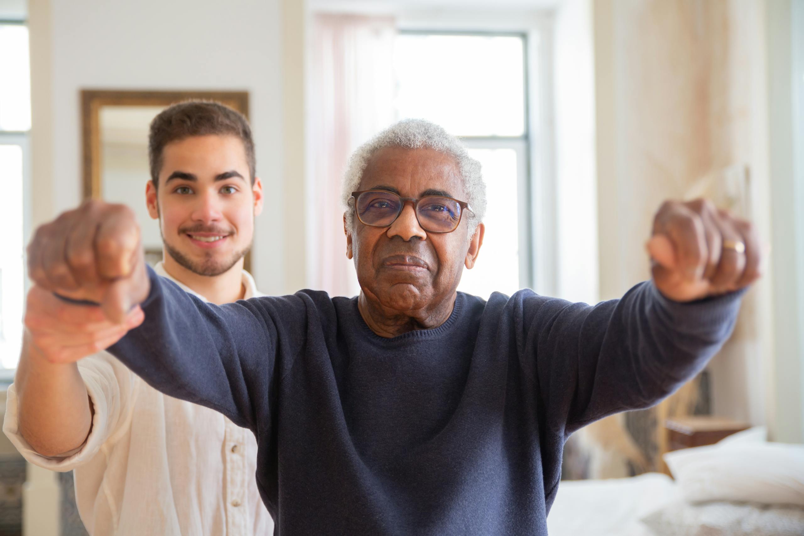 African American senior practicing balance with a young trainer in a bright room, promoting health and wellness.