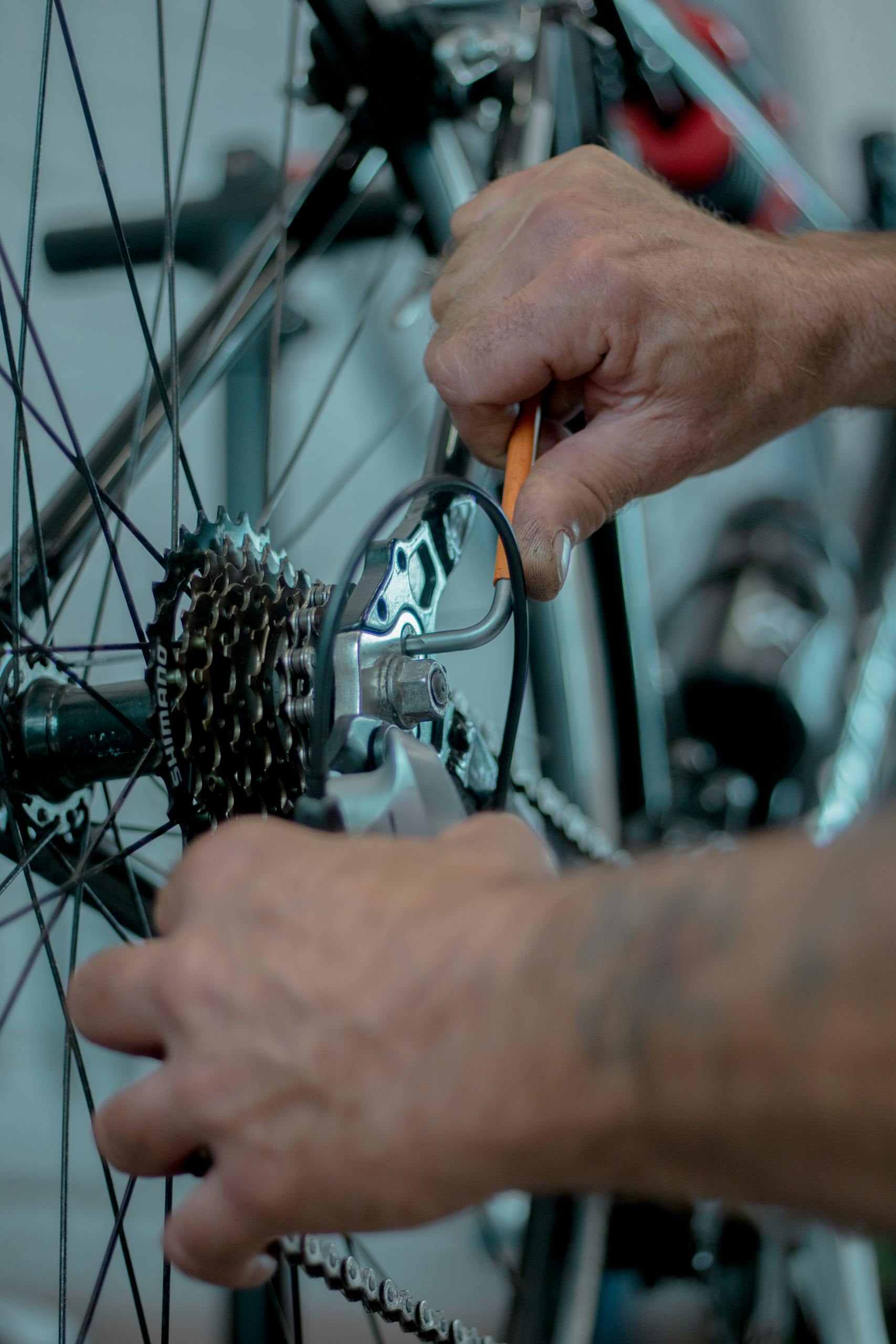 Detailed image of hands performing maintenance on a bicycle gear using tools.