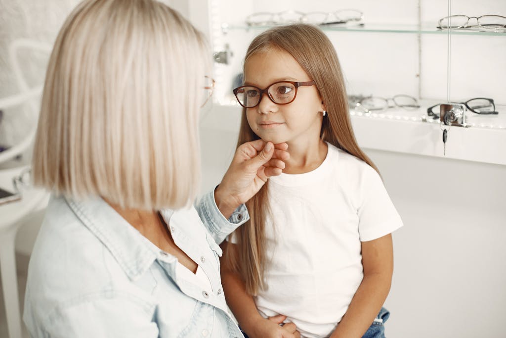A child being assisted by an optician while trying on new glasses in an eyewear shop.