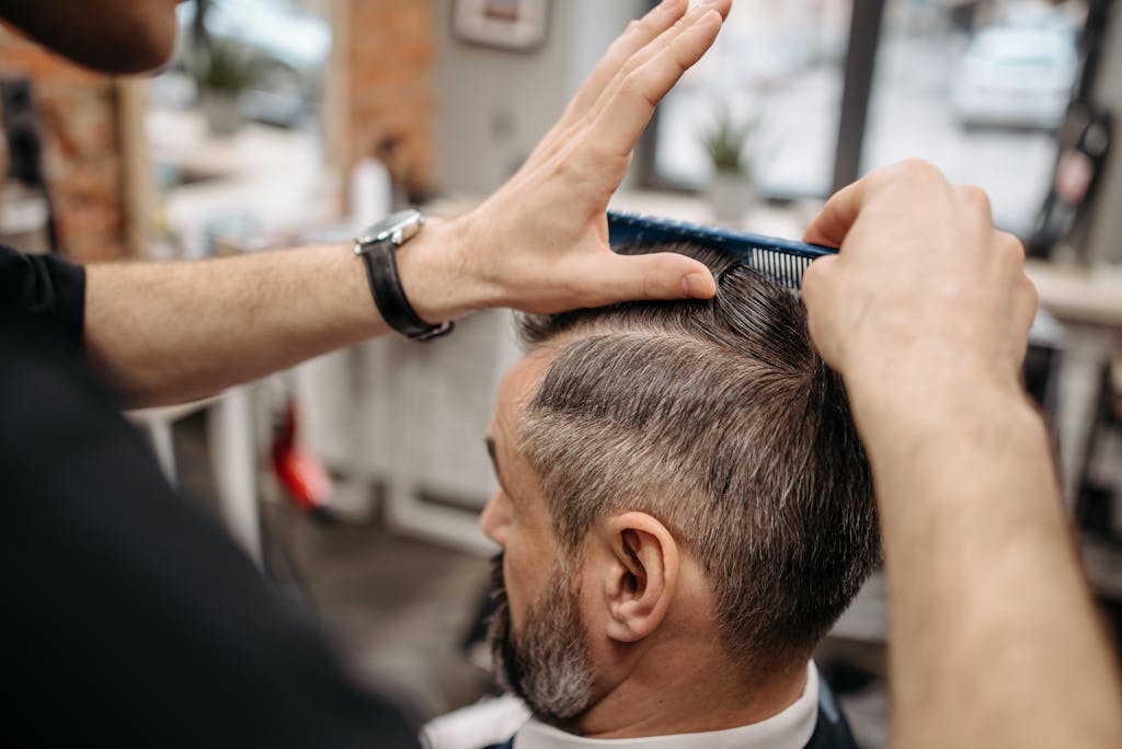 Close-up of a barber styling a customer's hair in a modern barbershop setting.