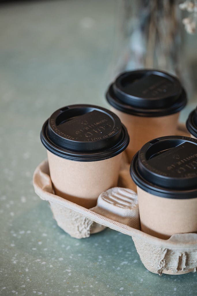 Close-up of eco-friendly paper coffee cups in a recyclable tray on a textured surface.