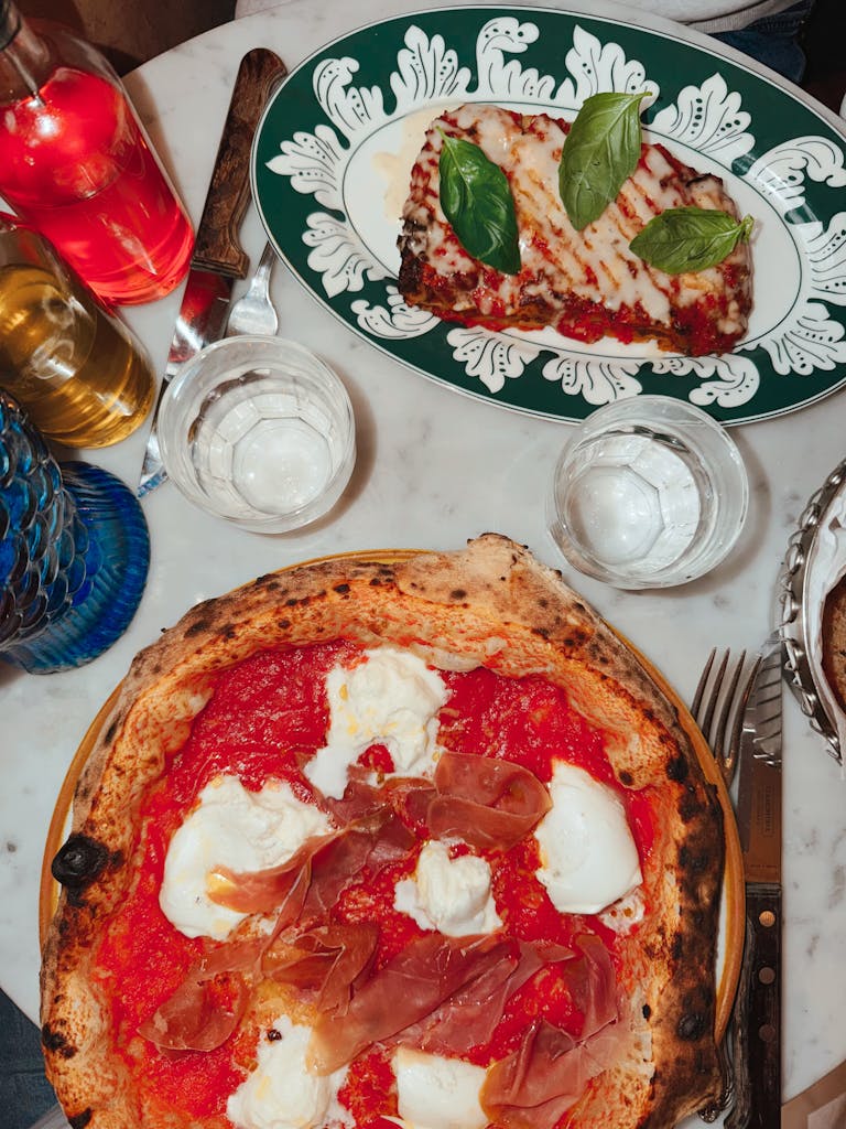 Top view of Italian pizza with ricotta and eggplant parmesan on a marble table.